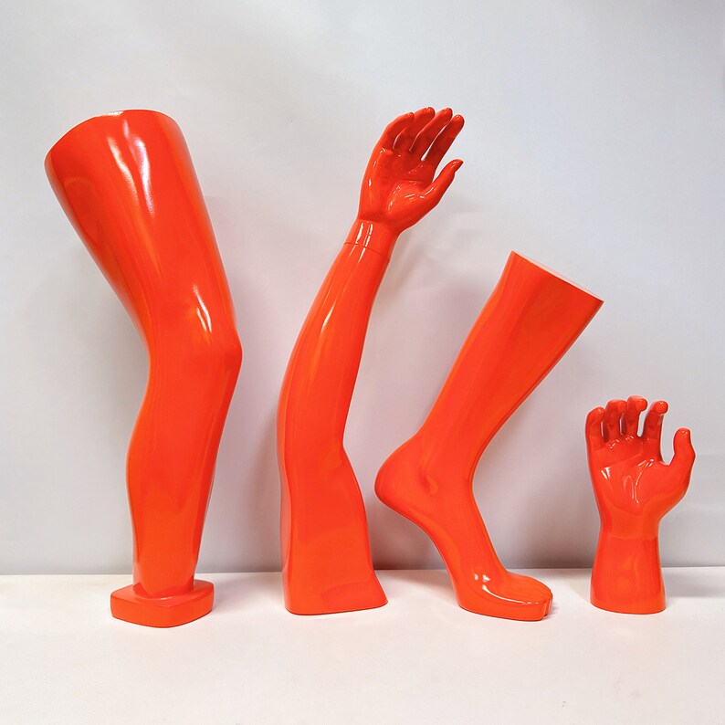 Maniquíes de fibra de vidrio naranja para exhibición: formas de mano, brazo, rodilla y pie para venta minorista de ropa deportiva.